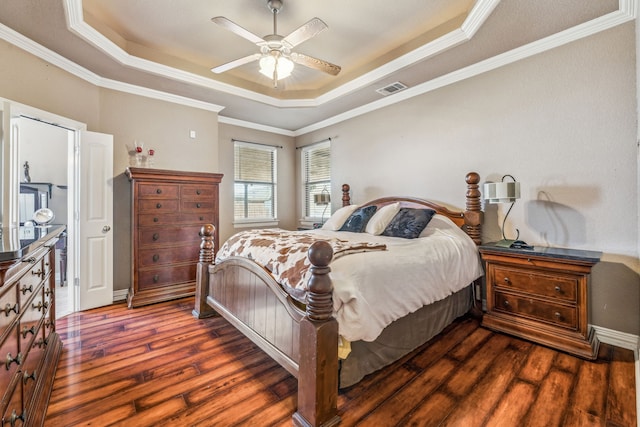 bedroom featuring a raised ceiling, crown molding, dark wood-style flooring, and visible vents