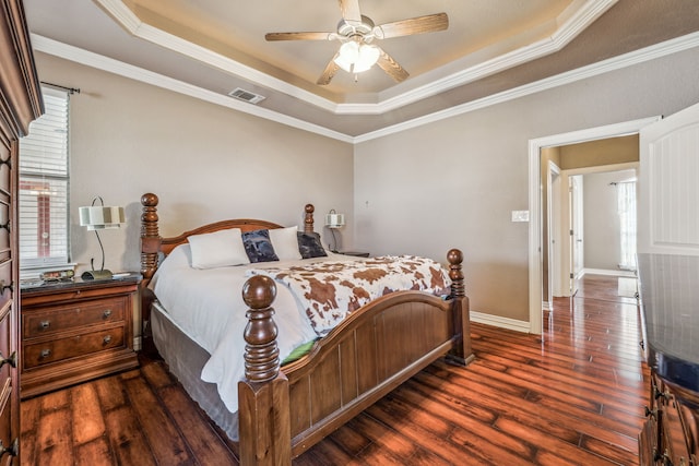 bedroom with hardwood / wood-style floors, visible vents, a tray ceiling, and multiple windows