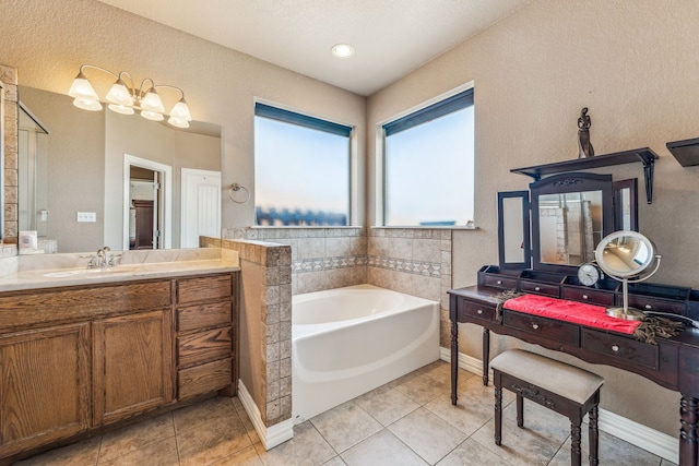 bathroom with baseboards, a textured wall, vanity, tile patterned flooring, and a garden tub