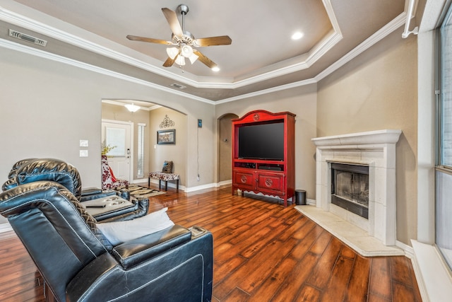 living room with visible vents, a raised ceiling, arched walkways, a ceiling fan, and wood finished floors