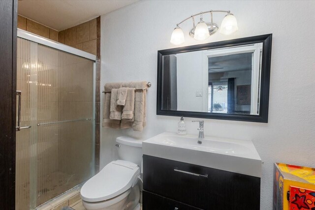 bathroom featuring vanity, a shower stall, and toilet