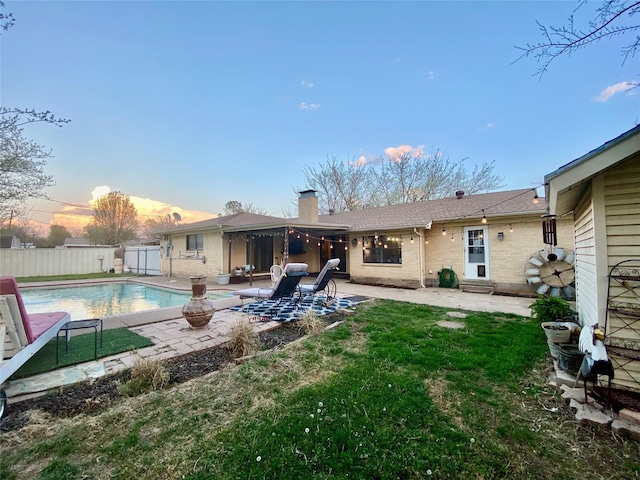 back of property featuring a fenced in pool, a chimney, fence private yard, a patio, and brick siding