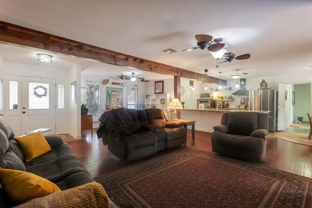 living room featuring wood finished floors, visible vents, beam ceiling, and ceiling fan