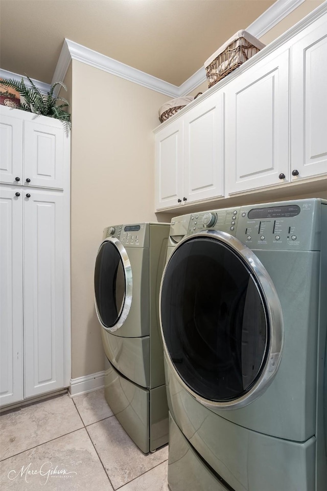 clothes washing area with ornamental molding, independent washer and dryer, cabinet space, and baseboards