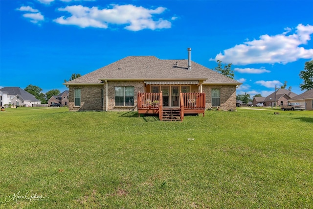 back of property featuring a lawn, a deck, a shingled roof, and brick siding