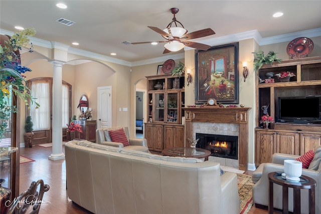 living area with visible vents, ceiling fan, arched walkways, ornate columns, and a tiled fireplace