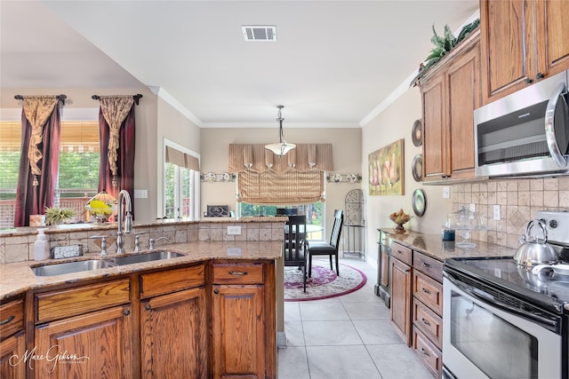 kitchen featuring a sink, appliances with stainless steel finishes, visible vents, brown cabinetry, and backsplash