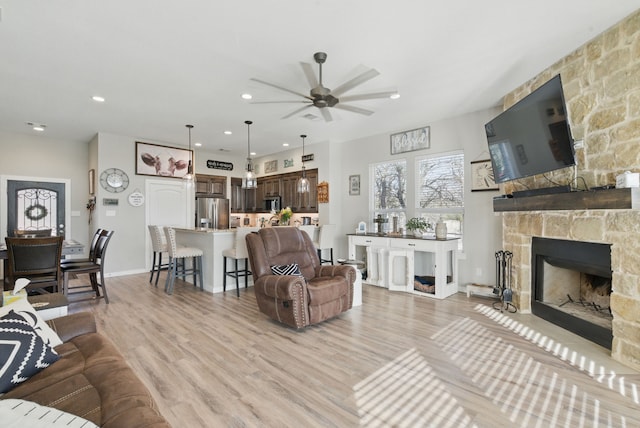 living room featuring a fireplace, light wood-style floors, recessed lighting, and a ceiling fan