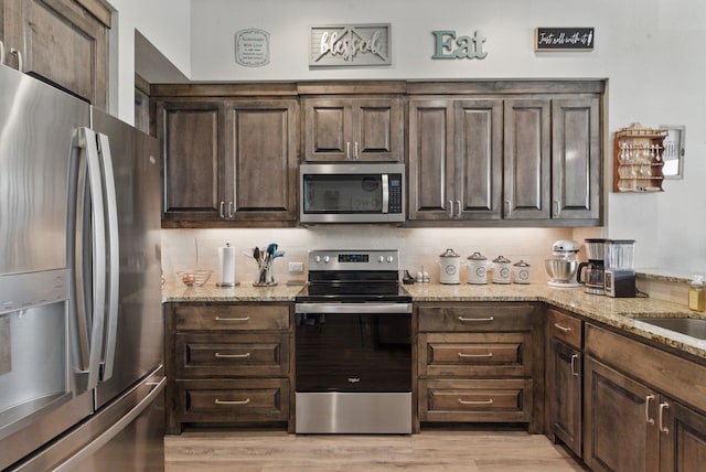 kitchen featuring dark brown cabinetry, backsplash, and appliances with stainless steel finishes