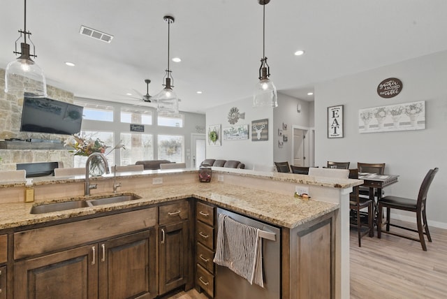 kitchen featuring open floor plan, visible vents, a sink, ceiling fan, and light stone countertops