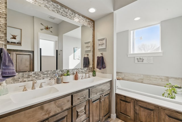 bathroom featuring double vanity, tasteful backsplash, a sink, and a garden tub
