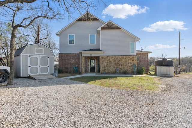 view of front of house featuring a storage unit, stone siding, an outdoor structure, and brick siding