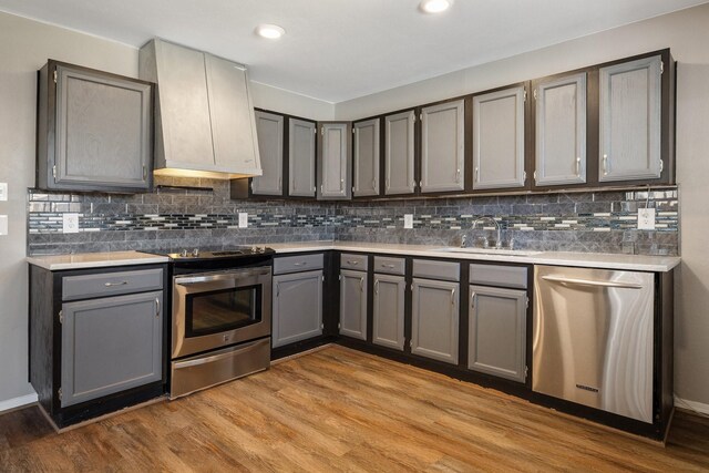 kitchen with gray cabinetry, light wood-style flooring, stainless steel appliances, and a sink