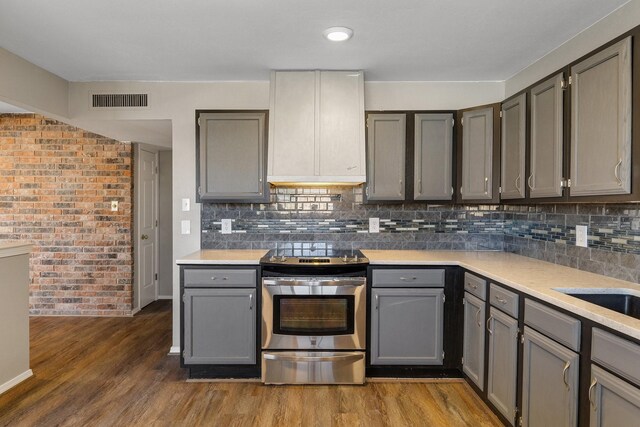 kitchen featuring visible vents, wood finished floors, stainless steel range with electric cooktop, light countertops, and gray cabinetry