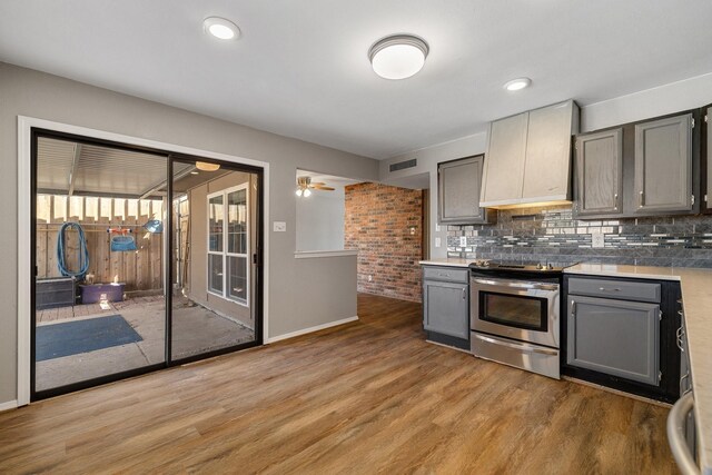 kitchen with light wood-style floors, stainless steel range with electric stovetop, gray cabinets, backsplash, and visible vents