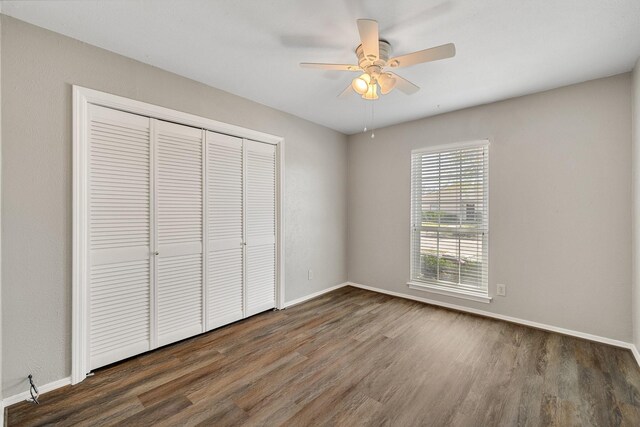 unfurnished bedroom featuring baseboards, wood finished floors, and a closet