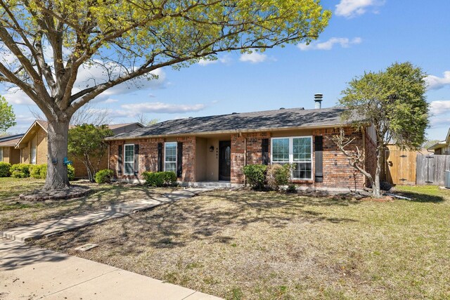 ranch-style home with brick siding, fence, a shingled roof, and a front yard