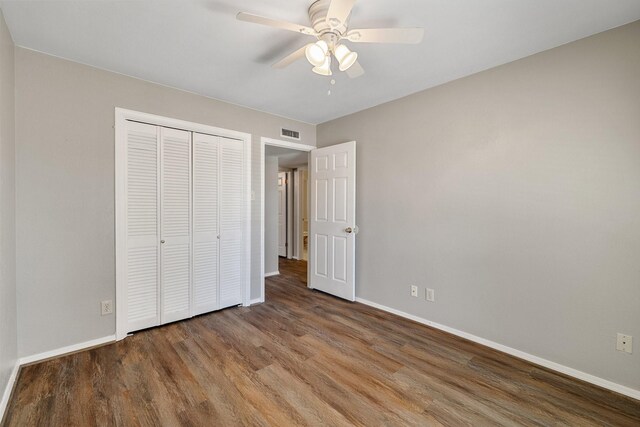 unfurnished bedroom with baseboards, visible vents, wood finished floors, and a closet