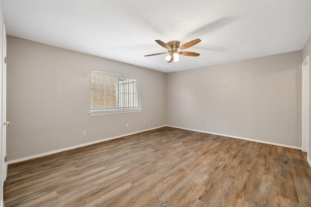 spare room with baseboards, ceiling fan, and wood finished floors