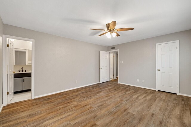 unfurnished bedroom featuring light wood-style floors, a sink, baseboards, and visible vents
