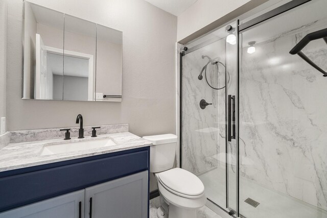 bathroom with a marble finish shower, vanity, and toilet