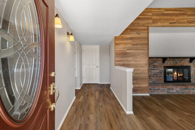 hall featuring wooden walls, baseboards, and wood finished floors