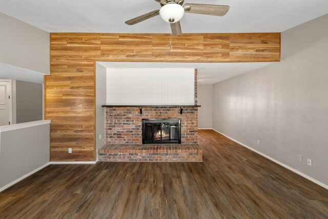 unfurnished living room with baseboards, a ceiling fan, wood finished floors, and a brick fireplace