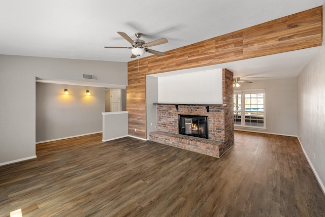 unfurnished living room featuring ceiling fan, visible vents, a fireplace, dark wood finished floors, and wood walls