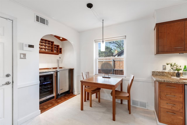 6814 Blackwood Dr, Dallas, TX 75231 - dining room featuring wine cooler, bar with sink, crown molding, a wainscoted wall, and arched walkways