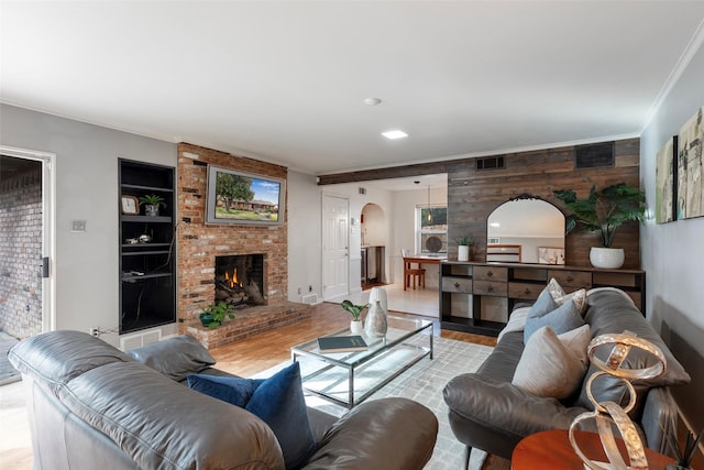 6814 Blackwood Dr, Dallas, TX 75231 - living area with arched walkways, built in shelves, light wood-style floors, crown molding, and wooden walls