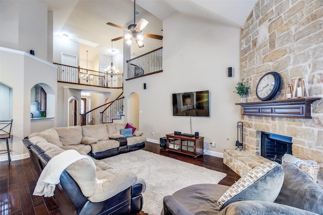3533 Hutch Dr, Plano, TX 75074 - living room featuring arched walkways, a stone fireplace, ceiling fan with notable chandelier, stairs, and dark wood-style floors