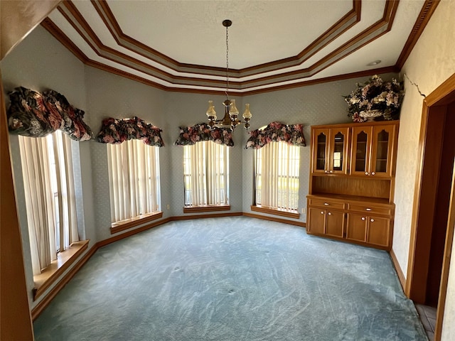 unfurnished dining area with baseboards, ornamental molding, carpet floors, a tray ceiling, and a notable chandelier