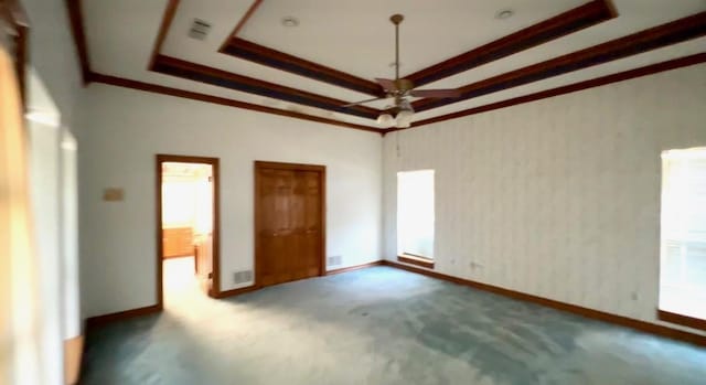 unfurnished bedroom featuring carpet flooring, crown molding, baseboards, wallpapered walls, and a raised ceiling