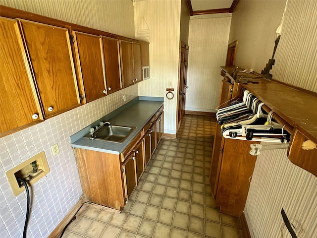 kitchen with wallpapered walls, a sink, visible vents, brown cabinetry, and light floors