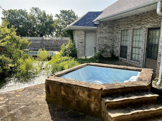 view of swimming pool featuring fence and an outdoor hot tub