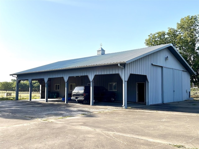 view of car parking featuring a carport, fence, and a pole building