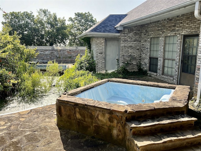 view of pool with an outdoor hot tub and fence