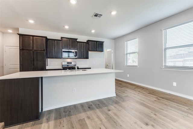 2004 Saddle Way, Mesquite, TX 75149 - kitchen featuring light wood-style floors, an island with sink, visible vents, light countertops, and stainless steel appliances