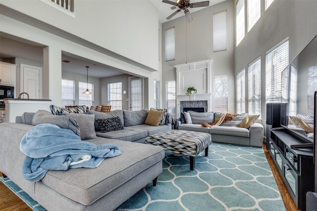 8106 Persimmon St, Irving, TX 75063 - living room featuring a high ceiling, ceiling fan, wood finished floors, healthy amount of natural light, and a fireplace