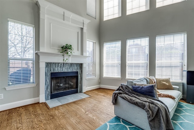 8106 Persimmon St, Irving, TX 75063 - living room featuring wood finished floors, baseboards, plenty of natural light, a high end fireplace, and a towering ceiling