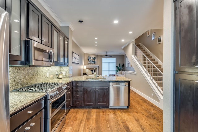 kitchen featuring ceiling fan, a peninsula, ornamental molding, a sink, and stainless steel appliances