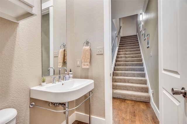 3204 Wycliff Ave Unit 3214, Dallas, TX 75219 - bathroom with wood finished floors, a textured wall, toilet, and a sink