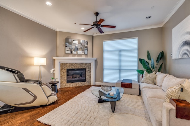 living area featuring ornamental molding, ceiling fan, recessed lighting, wood finished floors, and a glass covered fireplace