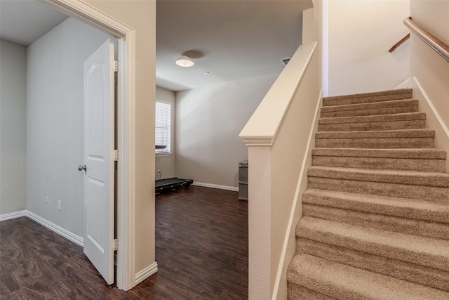 staircase featuring baseboards and wood finished floors