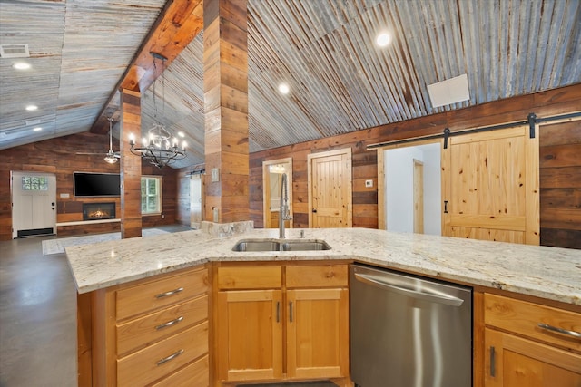 kitchen with wooden walls, a sink, light stone counters, open floor plan, and stainless steel dishwasher