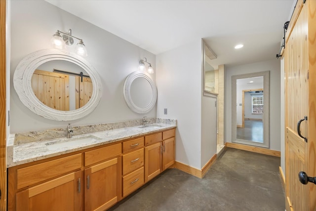 full bathroom with baseboards, double vanity, a sink, and concrete flooring