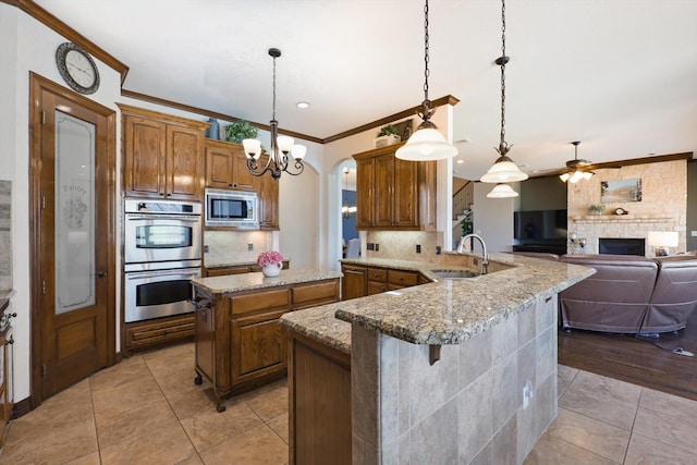 kitchen with stainless steel appliances, a sink, crown molding, ceiling fan, and backsplash