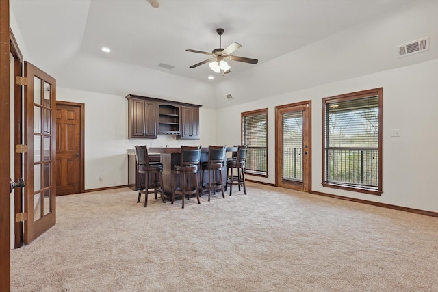 kitchen featuring open shelves, a breakfast bar area, light carpet, french doors, and baseboards