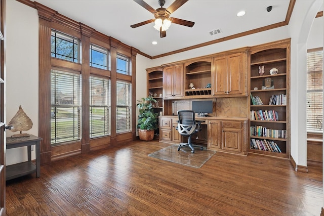 office area featuring built in desk, ceiling fan, ornamental molding, baseboards, and dark wood-style floors