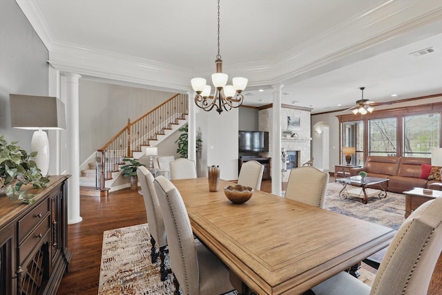 dining area featuring ornate columns, stairway, ornamental molding, ceiling fan, and dark wood finished floors